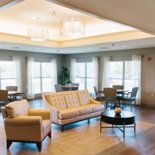 A modern living space with a comfortable sofa and chairs, featuring large windows and stylish lighting.