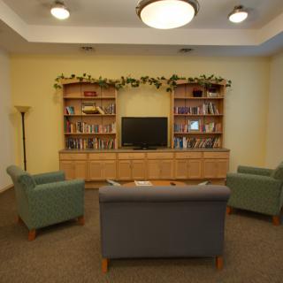 A cozy living room with bookshelves, a TV, and comfortable seating.