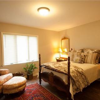 A cozy, traditionally decorated bedroom with a four-poster bed, warm lighting, and comfortable seating.