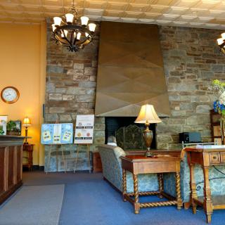 A cozy lobby with a stone wall and elegant lighting, featuring comfortable seating and a reception desk.