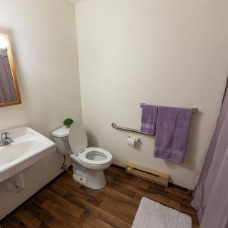 A clean bathroom with a toilet, sink, mirror, towel, and shower curtain.