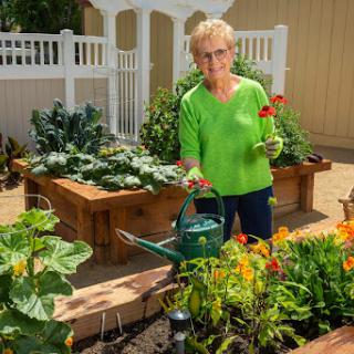 An elderly woman tends to her vibrant garden, showcasing her passion for gardening.