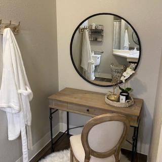 A modern vanity setup with a round mirror and wooden dressing table.