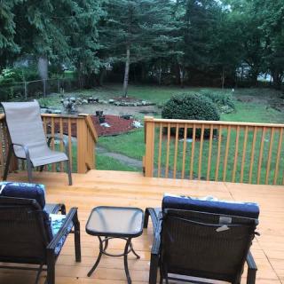 A cozy wooden deck with chairs and a table overlooking a lush backyard garden.