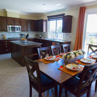A modern kitchen and dining area with wooden furniture and ample natural light.