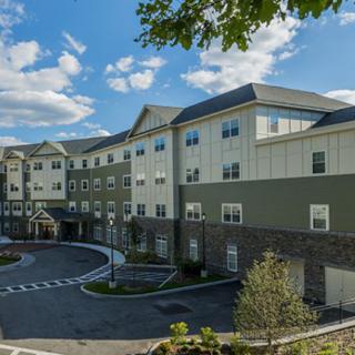 A modern residential building complex with landscaped surroundings under a bright blue sky.