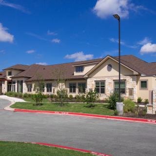 A modern residential building with well-maintained landscaping under a clear blue sky.