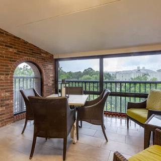 A spacious balcony with outdoor seating and a brick wall, offering a scenic view.