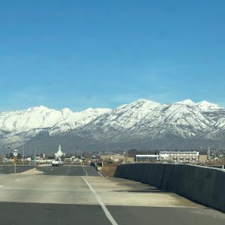 A scenic drive with snow-capped mountains under a clear blue sky.