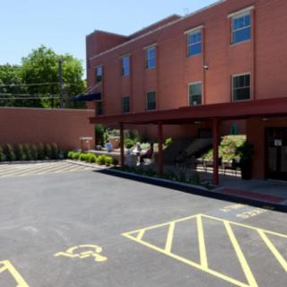 A brick building with a parking lot featuring accessible parking spaces on a sunny day.