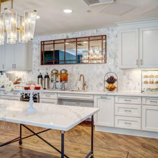 A stylish modern kitchen with marble countertops and elegant chandeliers.