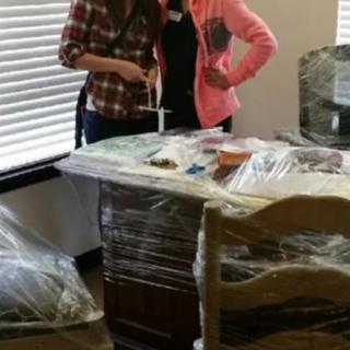 Two people standing next to a plastic-wrapped desk in an office setting.