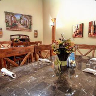 A cozy dining room with a marble table, wooden chairs, and decorative artwork on the walls.