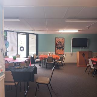 A cozy community dining area set up with orange decor and tables ready for an event.