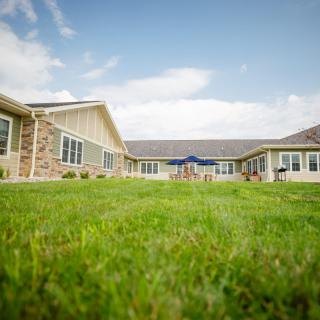 A wide-angle view of a building with a well-maintained lawn under a sunny sky.