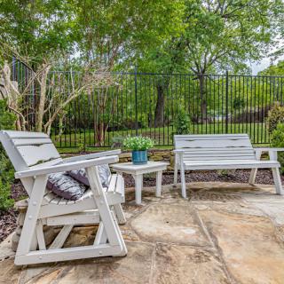 A cozy patio area with wooden furniture surrounded by a lush garden.