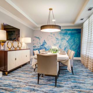 A modern dining room with a blue-themed decor and artistic wall mural, featuring contemporary furniture and elegant lighting.