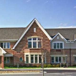 A large brick residential building with a peaked roof and multiple windows.