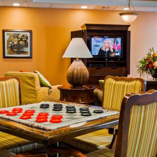 A cozy living room with a checkers game set up on a table, comfortable seating, and a television.
