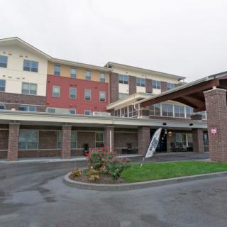 A modern multi-story building with a covered entrance and adjacent parking area.