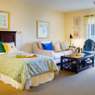 A cozy bedroom with a bed and a small living area featuring a sofa and coffee table.