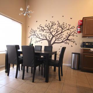 A modern dining area featuring a stylish tree mural and sleek furniture.