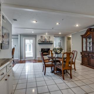 A spacious dining area with a round table and wooden chairs, featuring a tile floor and a china cabinet.