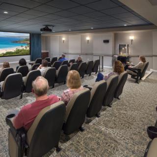An audience seated in a theater watching a movie on the big screen.