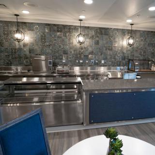 A modern commercial kitchen with stainless steel appliances and decorative lighting.