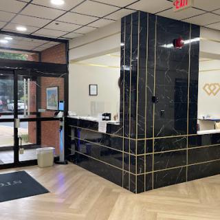 A modern reception area featuring a sleek black marble counter and warm wooden flooring, welcoming visitors into the lobby.