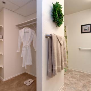 A bathroom with a hanging robe, towels, and simple decor.