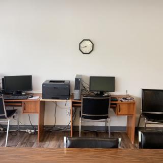 A quiet office space with several workstations equipped with computers and a printer.