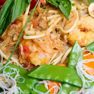 A delicious dish featuring shrimp pasta garnished with fresh basil and snow peas.