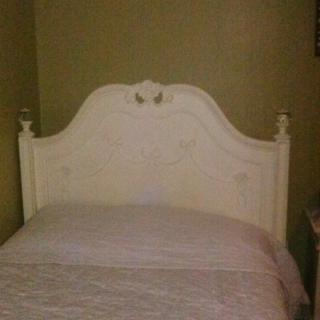 An antique-style bed with an ornate headboard in a bedroom.