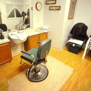An interior view of a barbershop with a styling chair, mirror, and sink.