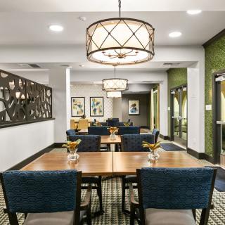 A modern dining area with stylish chandeliers, artwork, and neatly arranged tables and chairs.