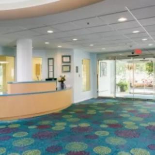 A modern lobby with a reception desk and colorful carpet.