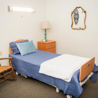A cozy hospital room featuring a bed, lamp, and decorative elements.