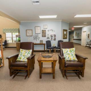 A cozy lobby seating area with two cushioned chairs and a small wooden table.
