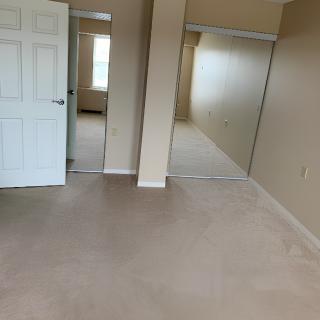 An empty bedroom with a carpeted floor and two closets.