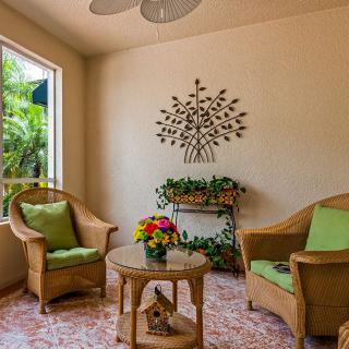A cozy indoor seating area with rattan chairs, green cushions, and decorative plants.
