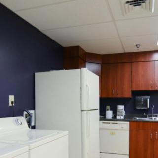 A kitchen with a refrigerator, dishwasher, and wooden cabinets.