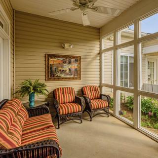 A cozy enclosed porch with comfortable seating and decorative elements.