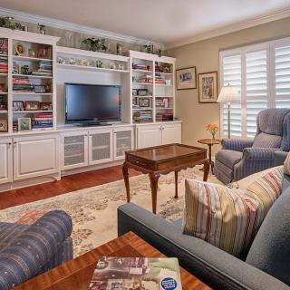 A cozy living room with armchairs, bookshelves, and a television.