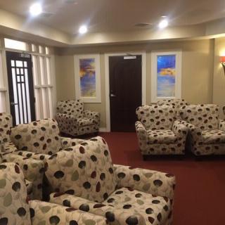 A cozy waiting room featuring patterned chairs, wall art, and warm lighting.