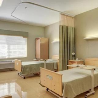 A clean and well-organized hospital room with two beds separated by a curtain.