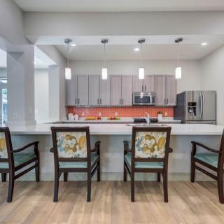 A modern kitchen interior with a sleek design, featuring a central counter with chairs and contemporary appliances.