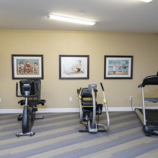 A gym room with exercise equipment including a treadmill and stationary bikes.
