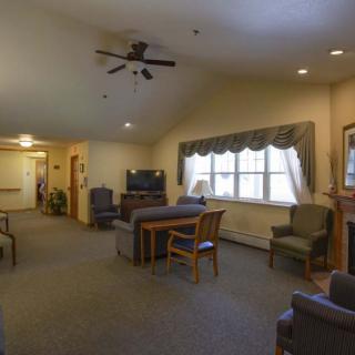 A cozy living room with a seating area, television, and ceiling fan.