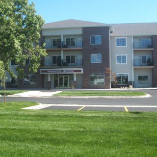 A modern apartment building with well-maintained lawns and parking area.